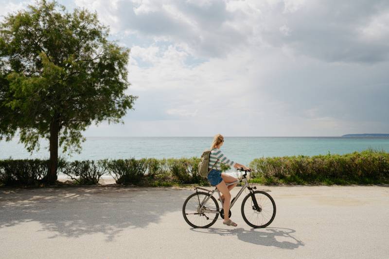 woman biking along the beach